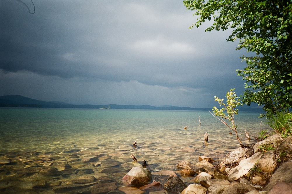 a body of water surrounded by rocks under a cloudy sky