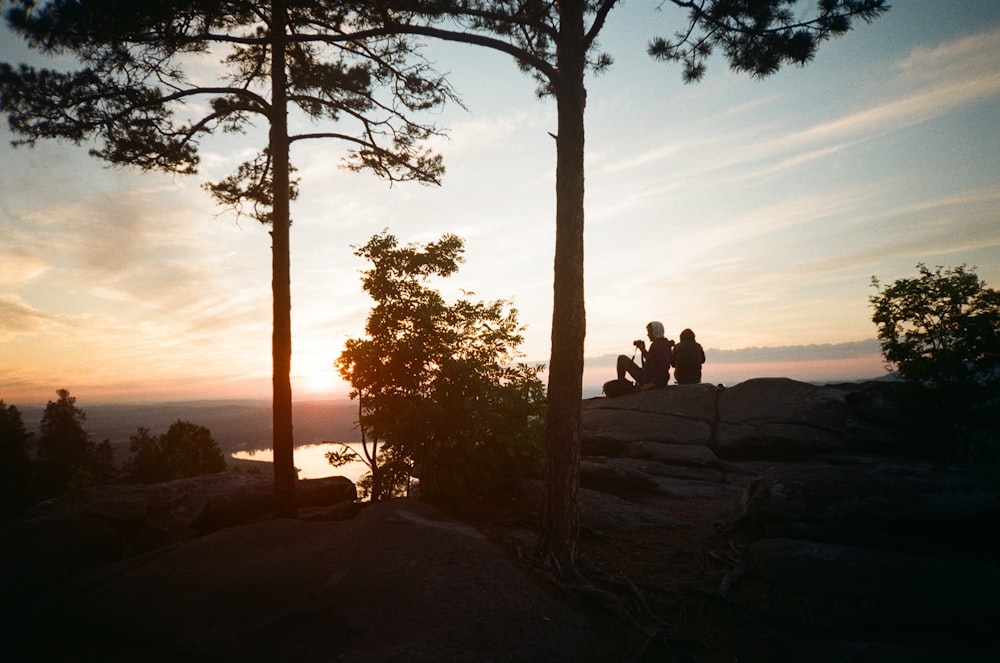 a couple of people sitting on top of a mountain