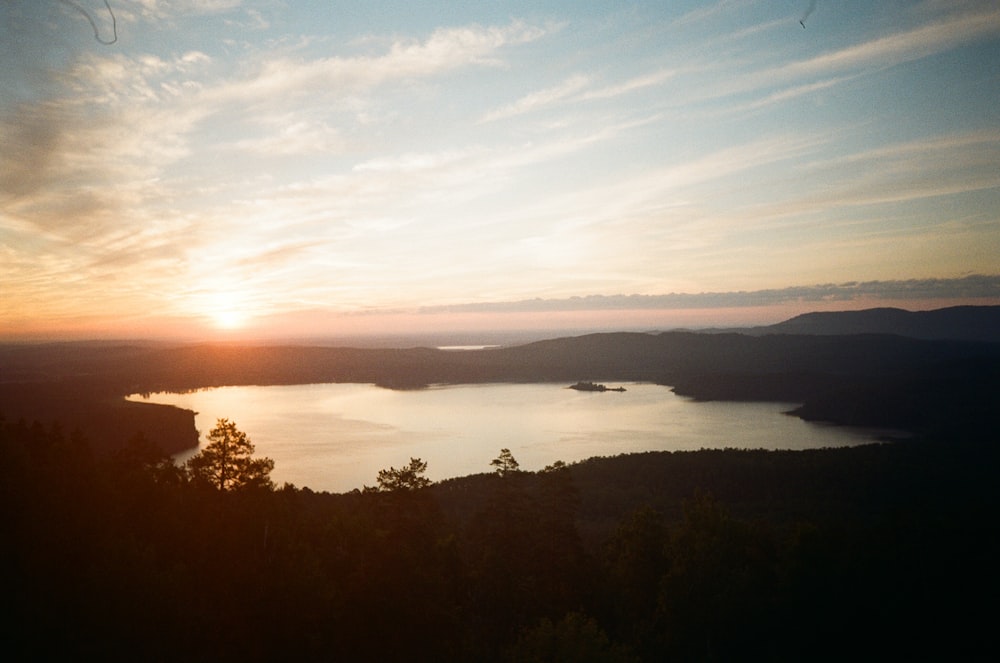 the sun is setting over a lake in the mountains