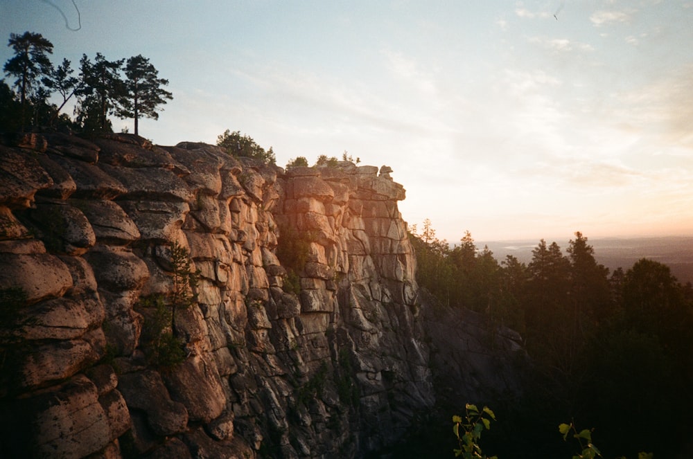 a rocky cliff with trees on top of it