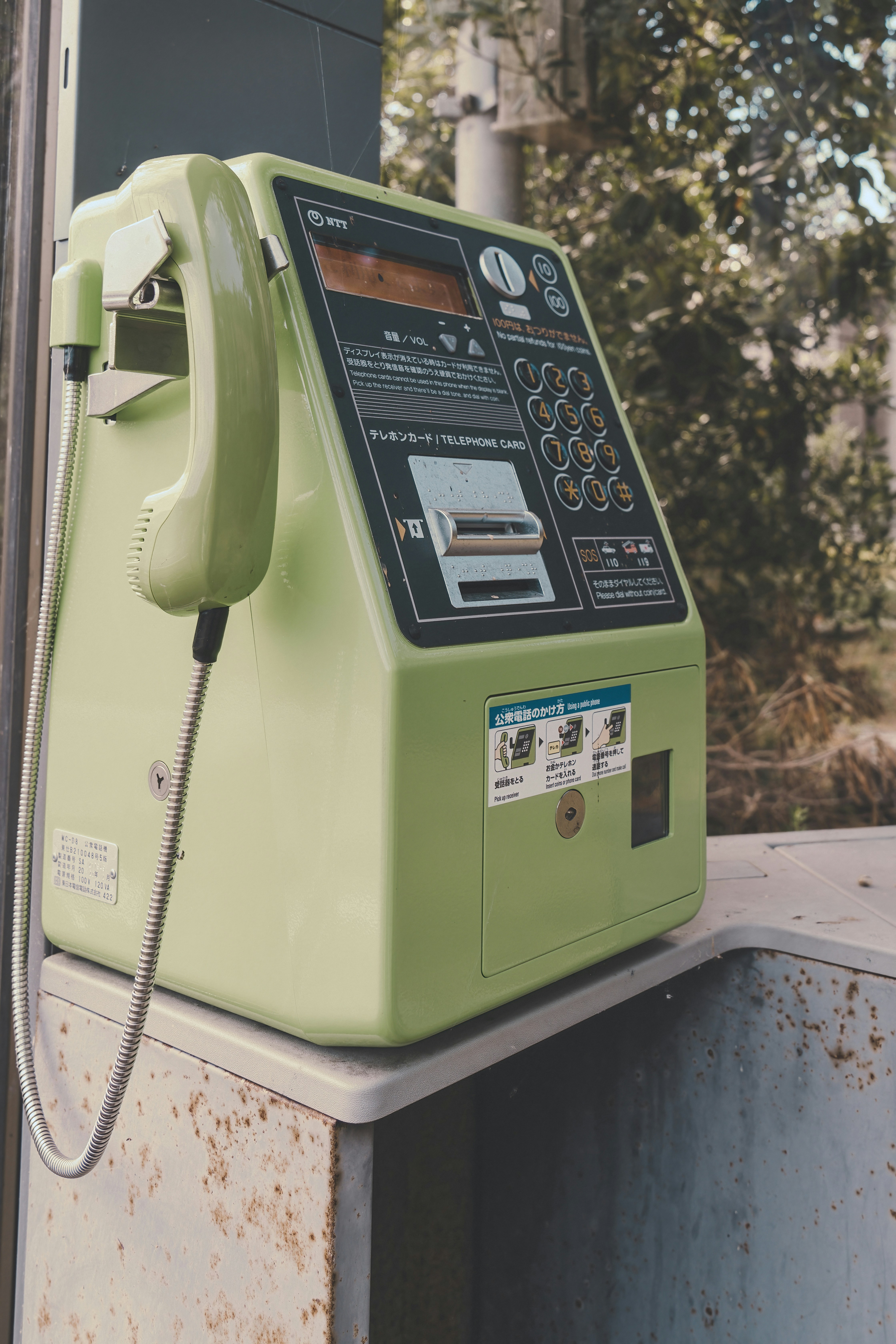 a green pay phone sitting on top of a metal box