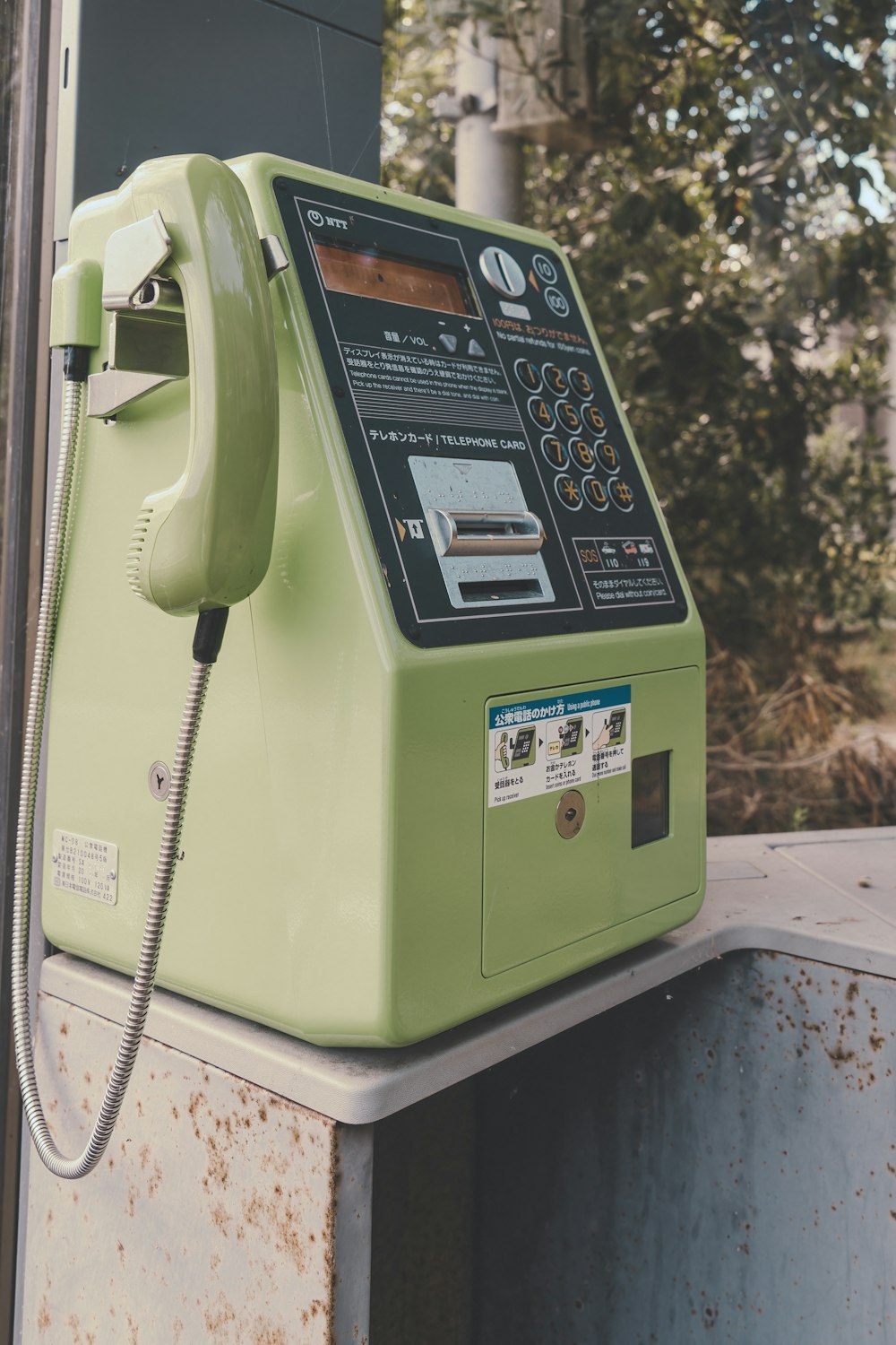 a green pay phone sitting on top of a metal box