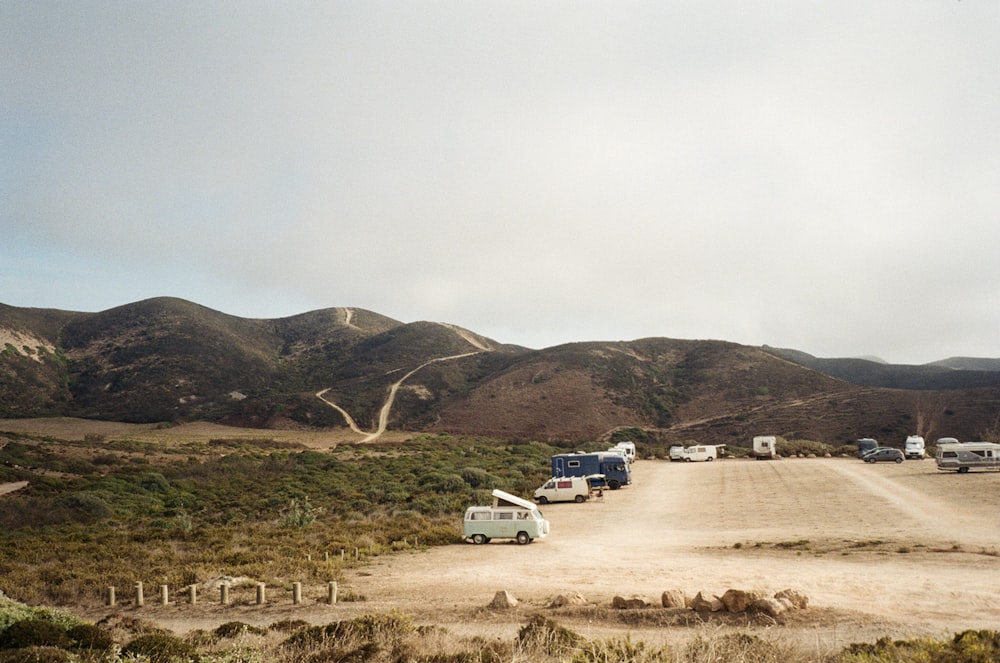 a group of vehicles parked on the side of a dirt road