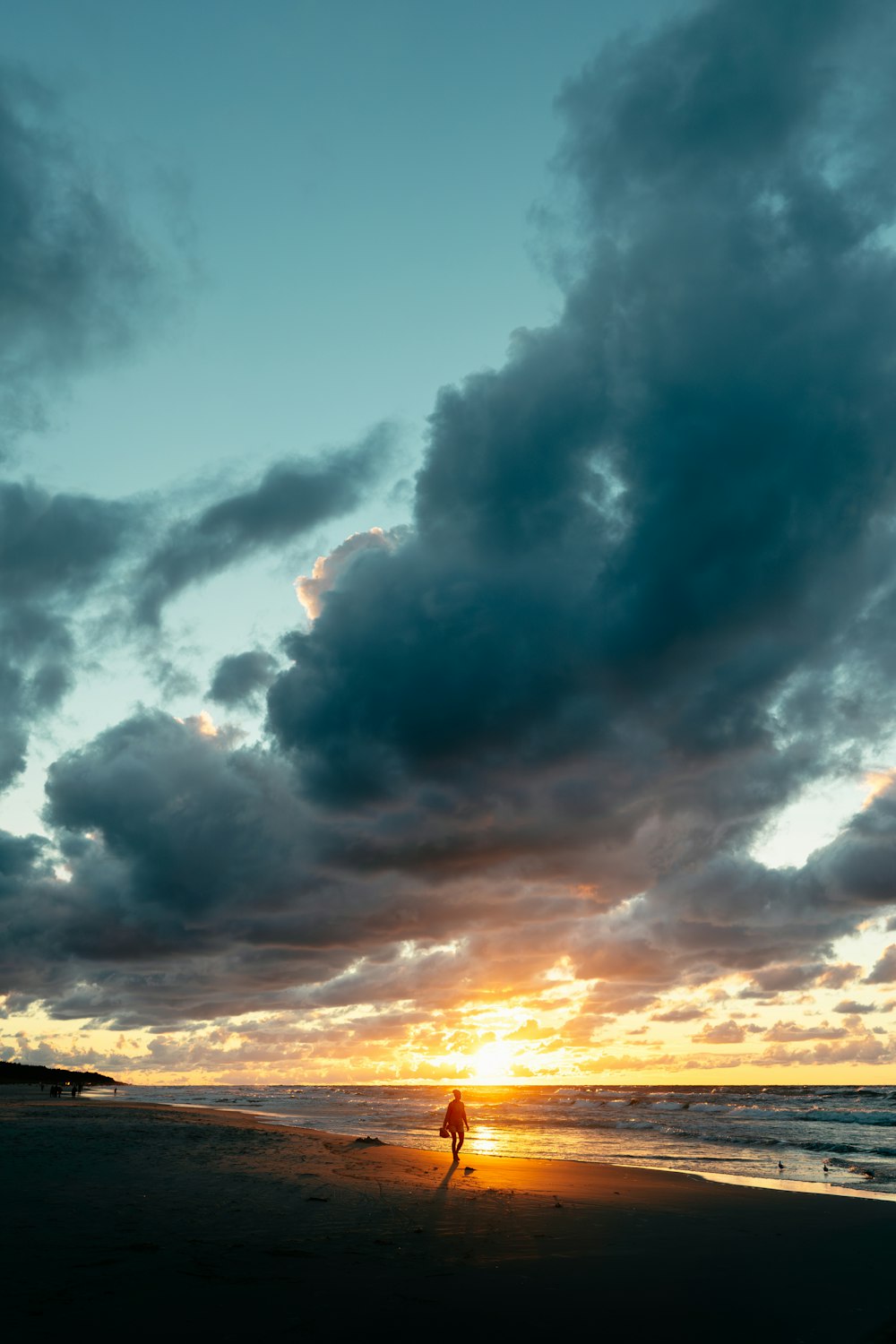 a person walking on a beach at sunset