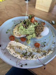 A vibrant brunch plate featuring avocado smash on sourdough, a poached egg, and fresh greens, styled with natural light.