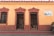 A small bookstore with two open doorways leading to shelves filled with books. The building has a rustic yellow facade with reddish-brown trim and architectural details. A sign next to the doorway reads 'Librería No 1 Barco de Papel' advertising book sales.