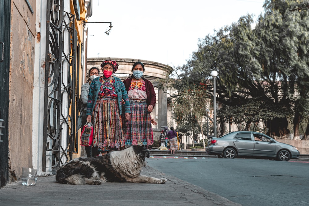 a group of people standing next to a dog on a street