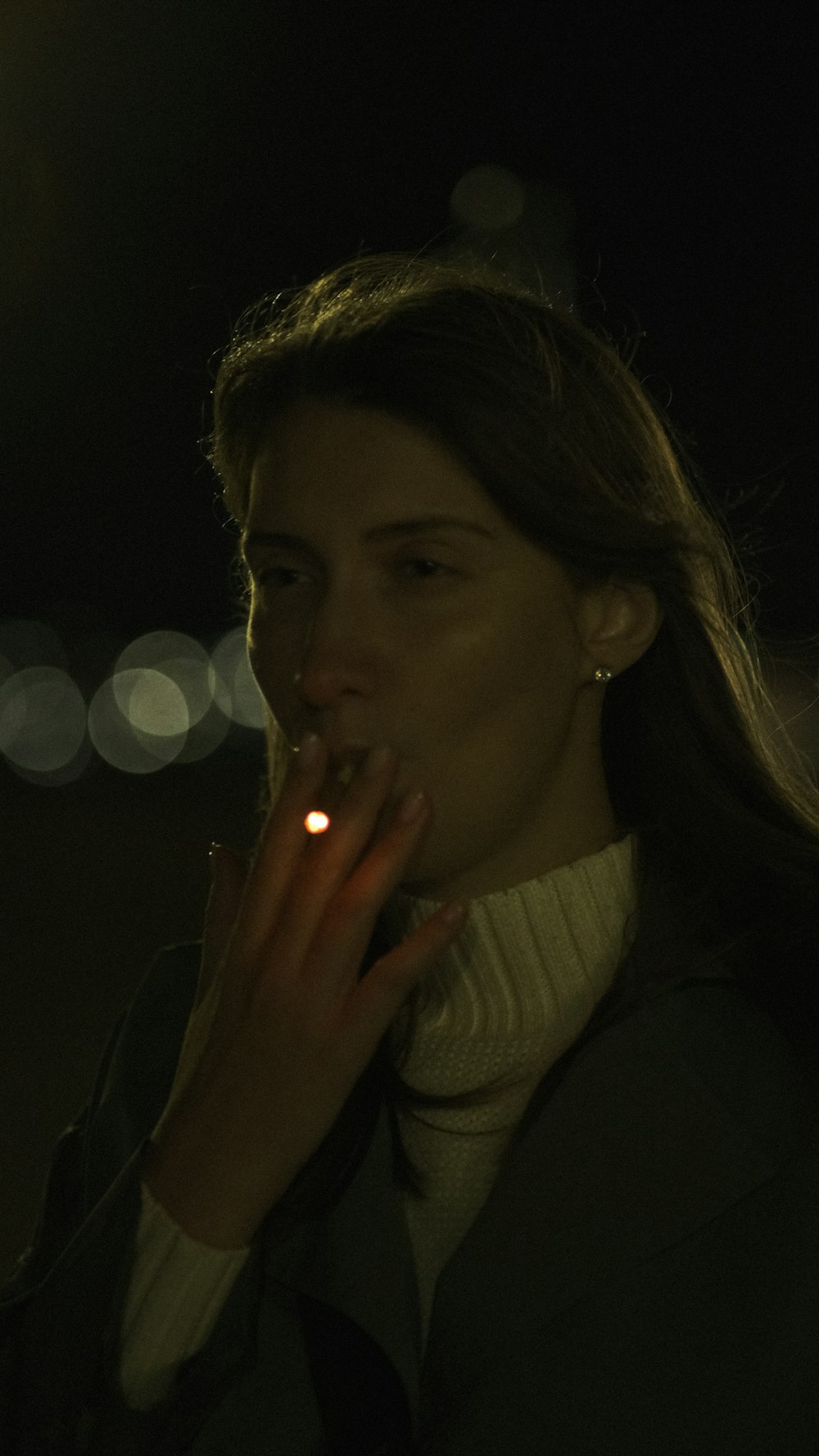 a woman is smoking a cigarette in the dark