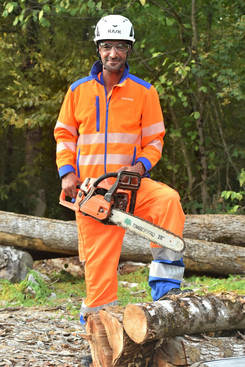 a man in an orange safety suit holding a chainsaw
