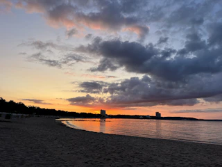 A sandy lot with a view of the calm bay waters at sunset.