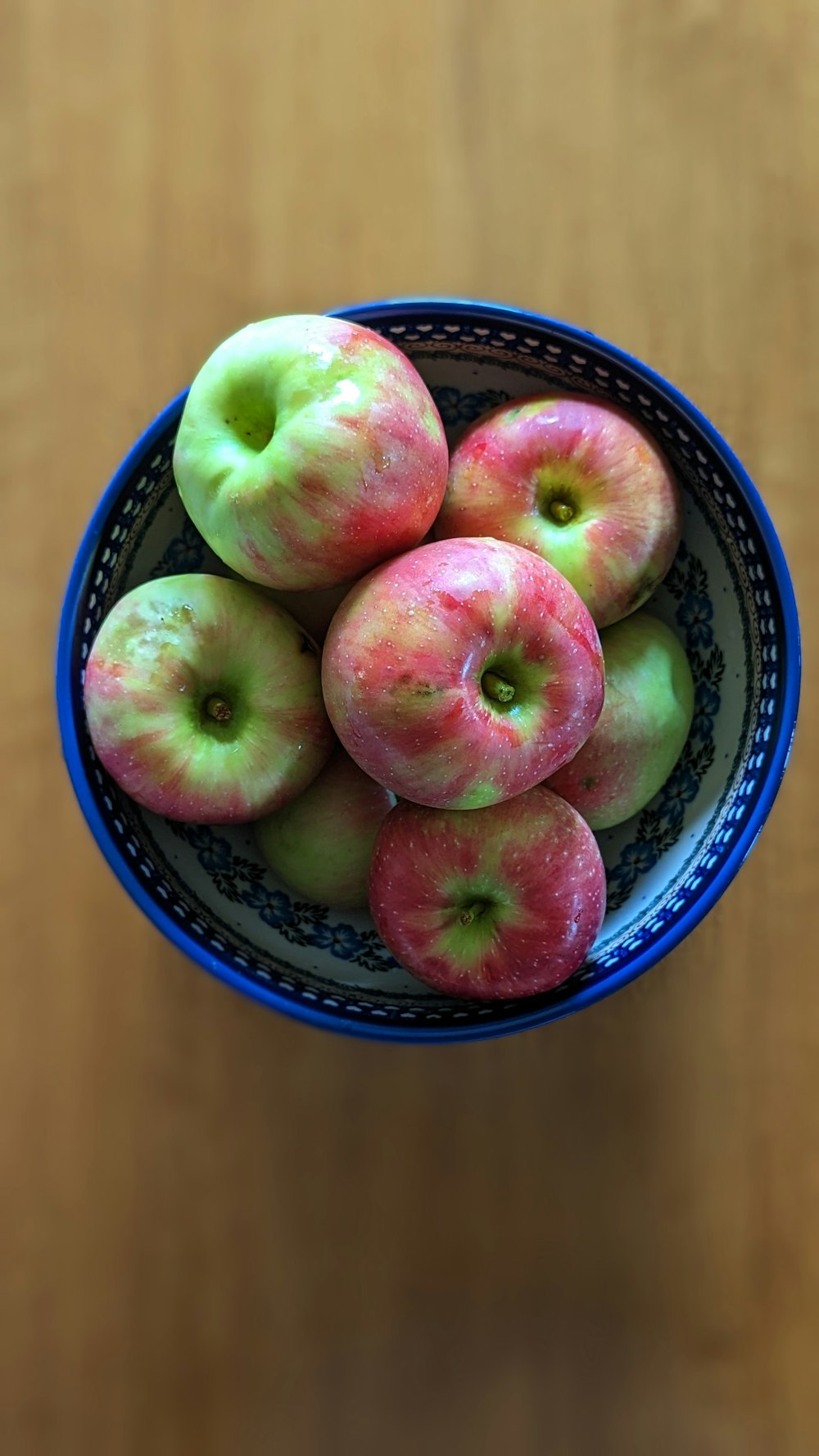 a blue bowl filled with green and red apples