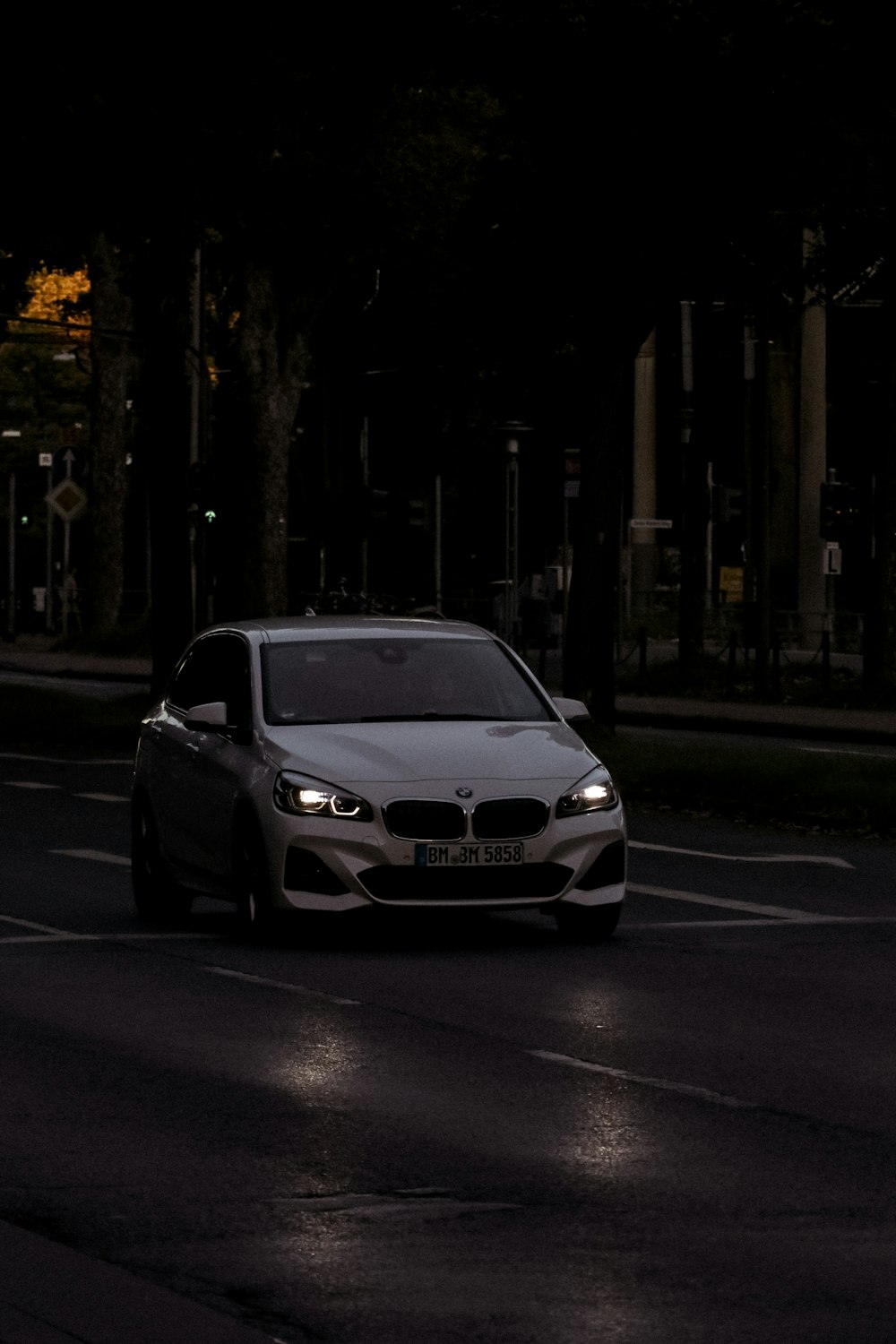 um carro branco dirigindo por uma rua à noite