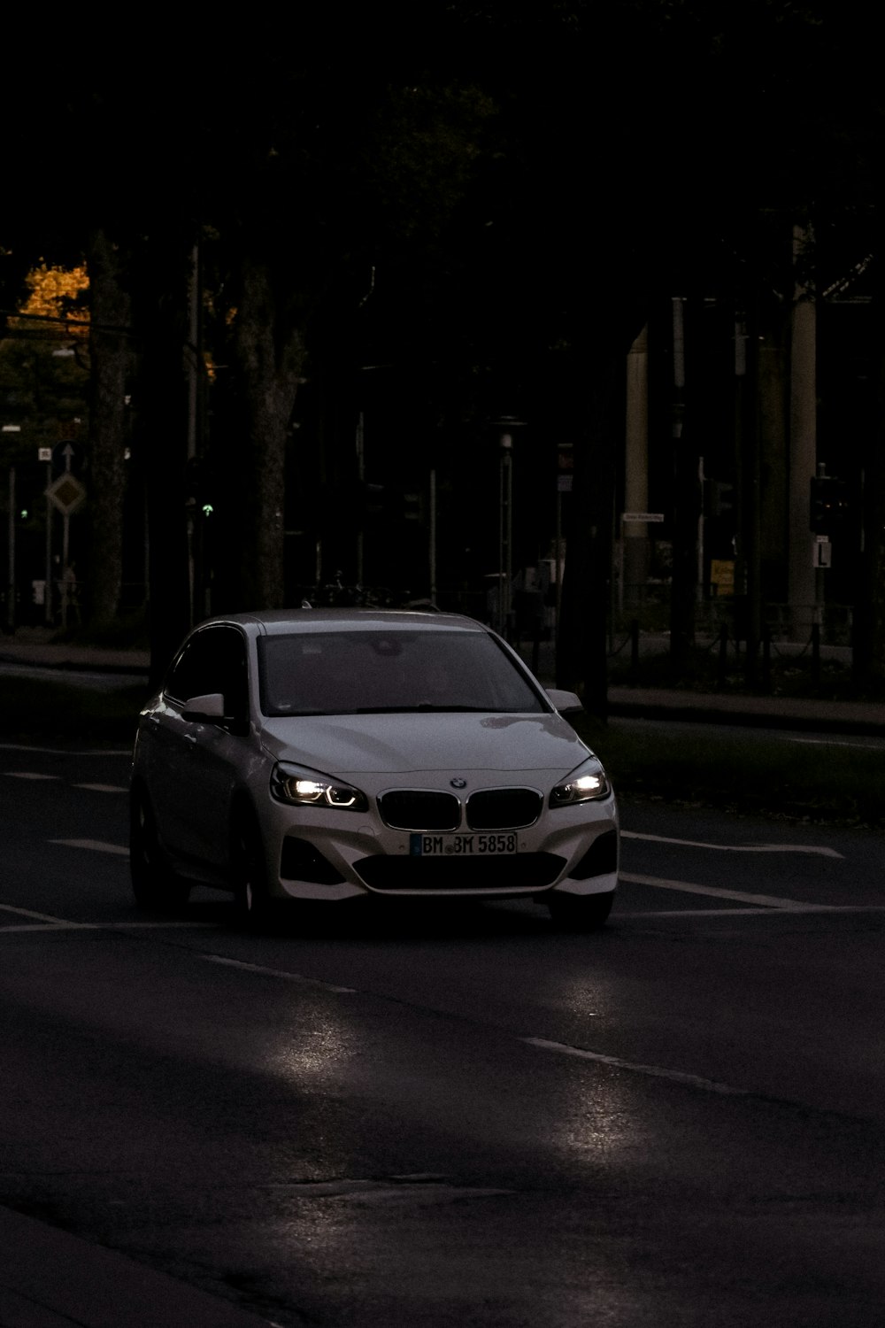 a white car driving down a street at night