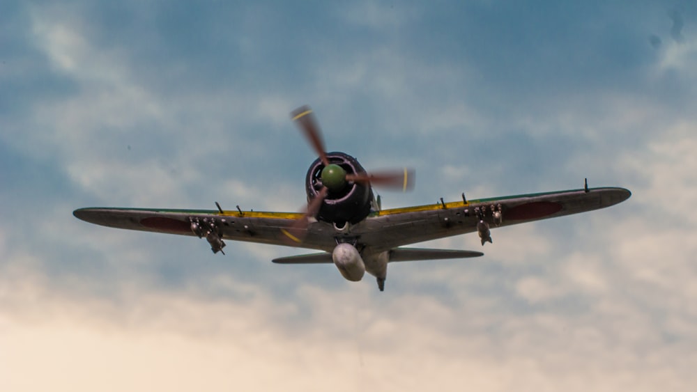 a small airplane flying through a cloudy blue sky