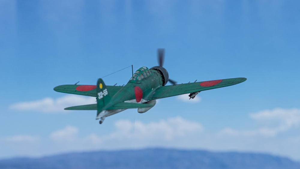 a small green airplane flying through a blue sky