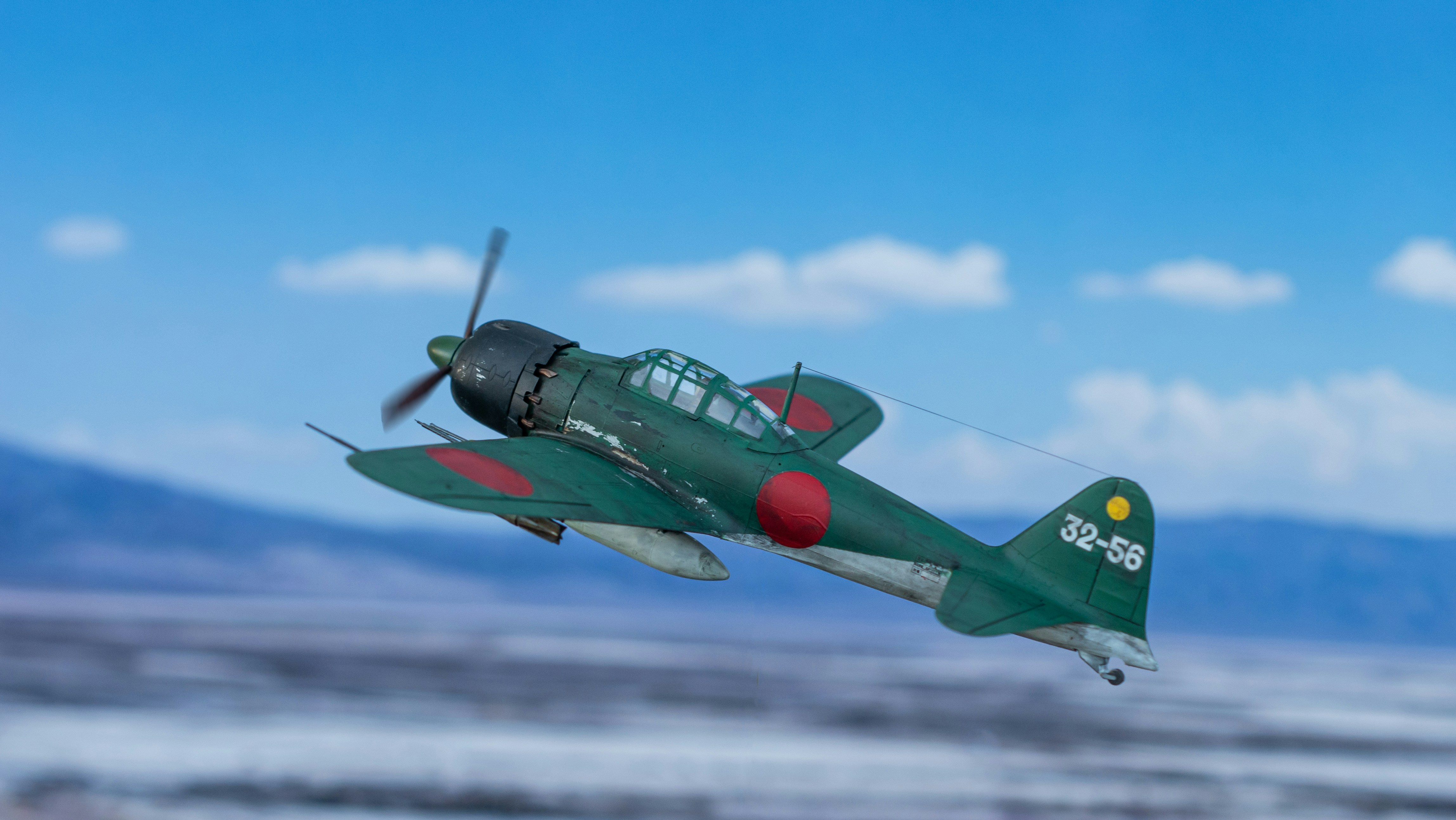 a small green airplane flying through a blue sky, My model of the Japanese A6M "Zero" fighter in 1:48