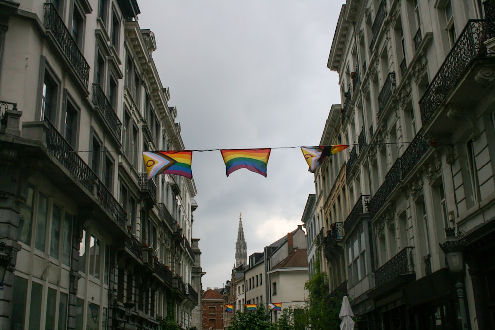 a rainbow colored kite hanging from a line between two buildings