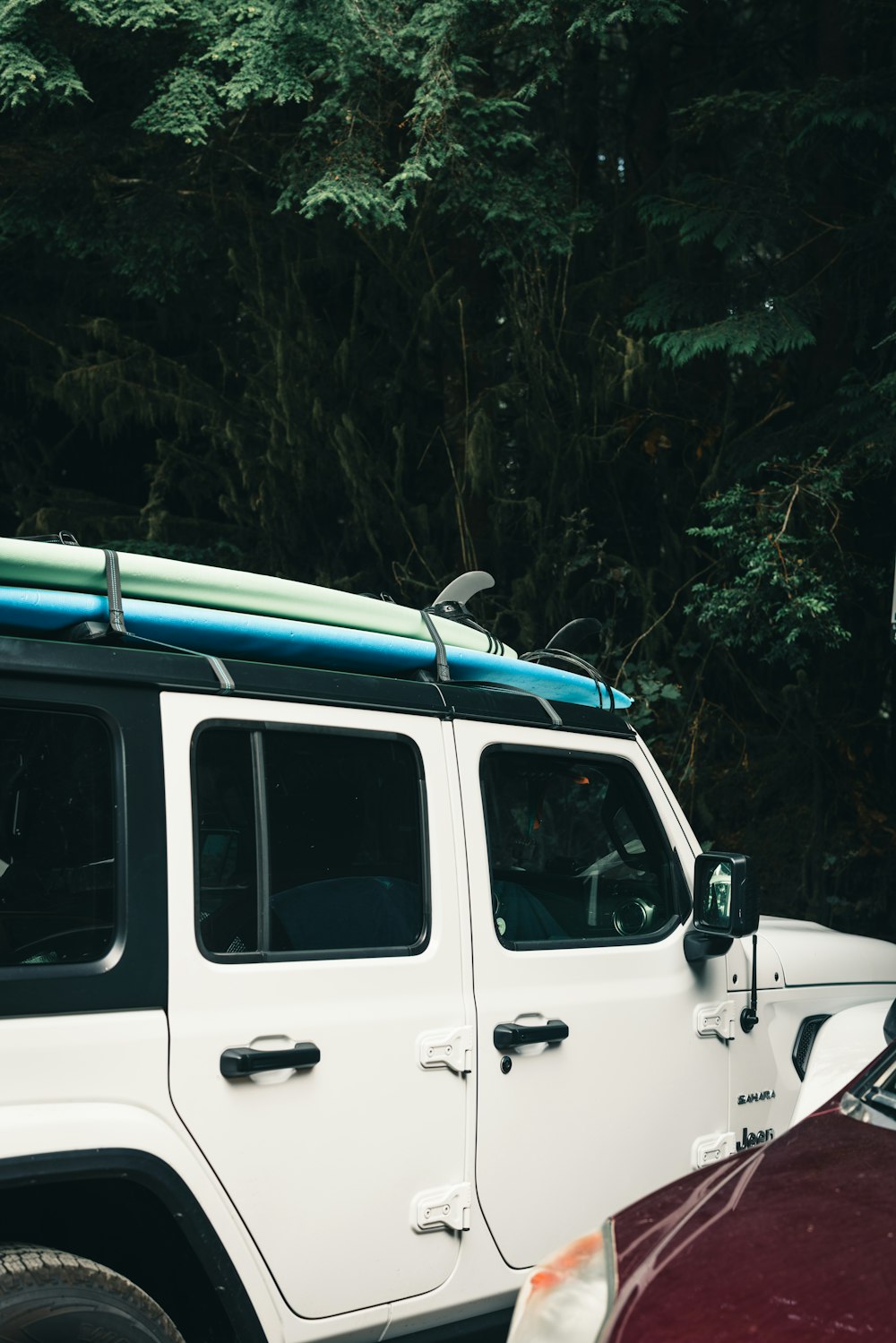 a white jeep with a surfboard on top of it