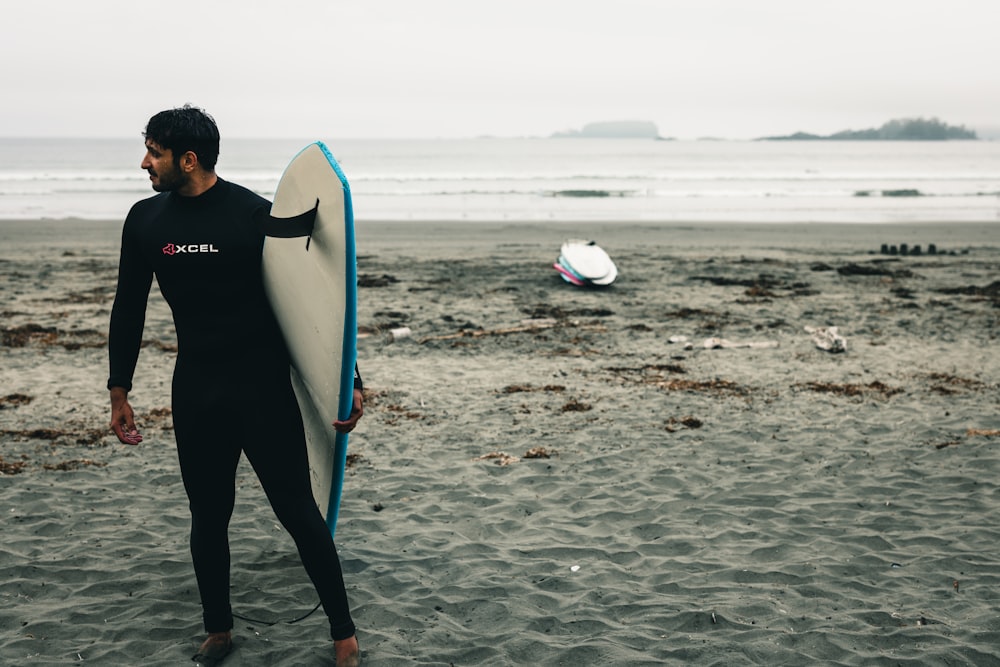 a man holding a surfboard on top of a sandy beach