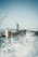 Cranes are positioned above a large industrial shipyard, with a dock and a partially visible ship. Water sprays in the foreground, adding a dynamic effect to the scene.
