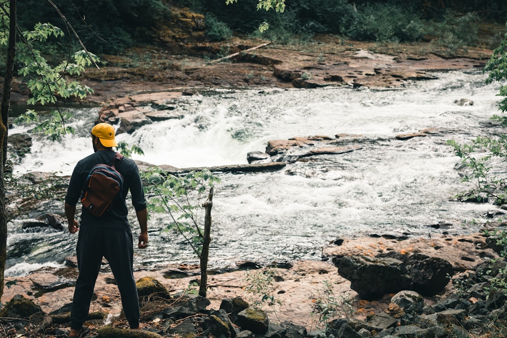 a man with a yellow hat standing in front of a river