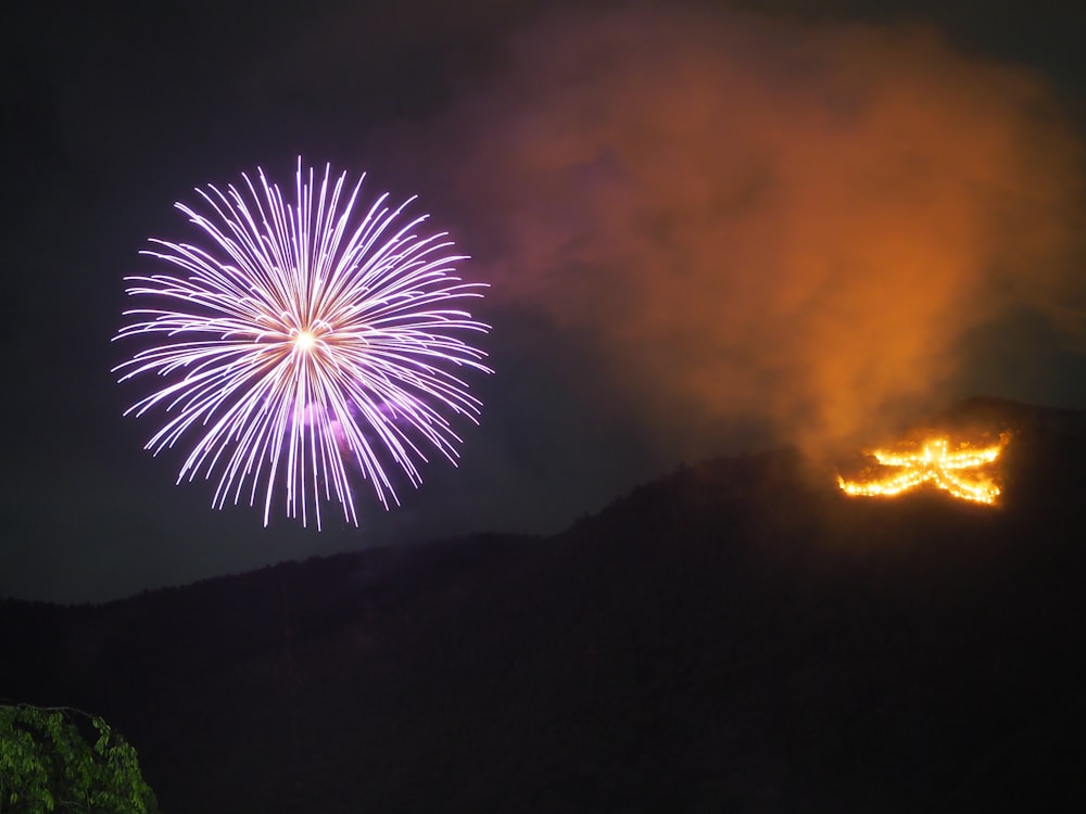 a fireworks display in the night sky with a mountain in the background