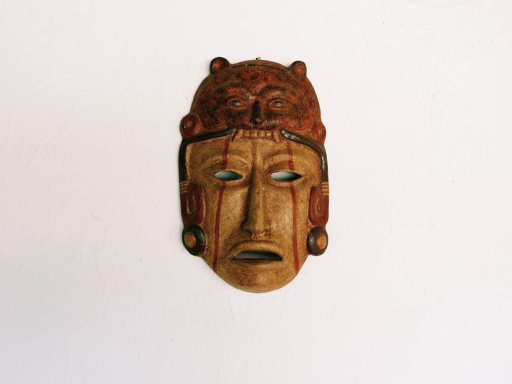 a wooden mask hanging on a white wall