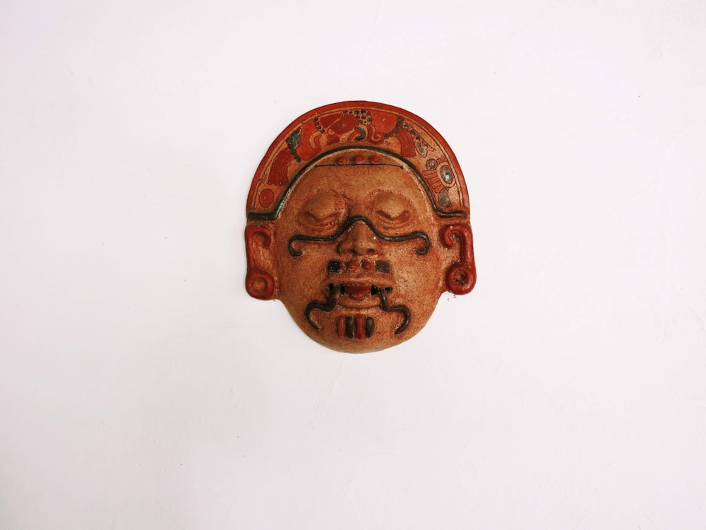 a wooden mask hanging on a white wall