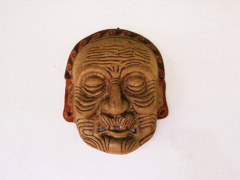 a wooden mask hanging on a white wall