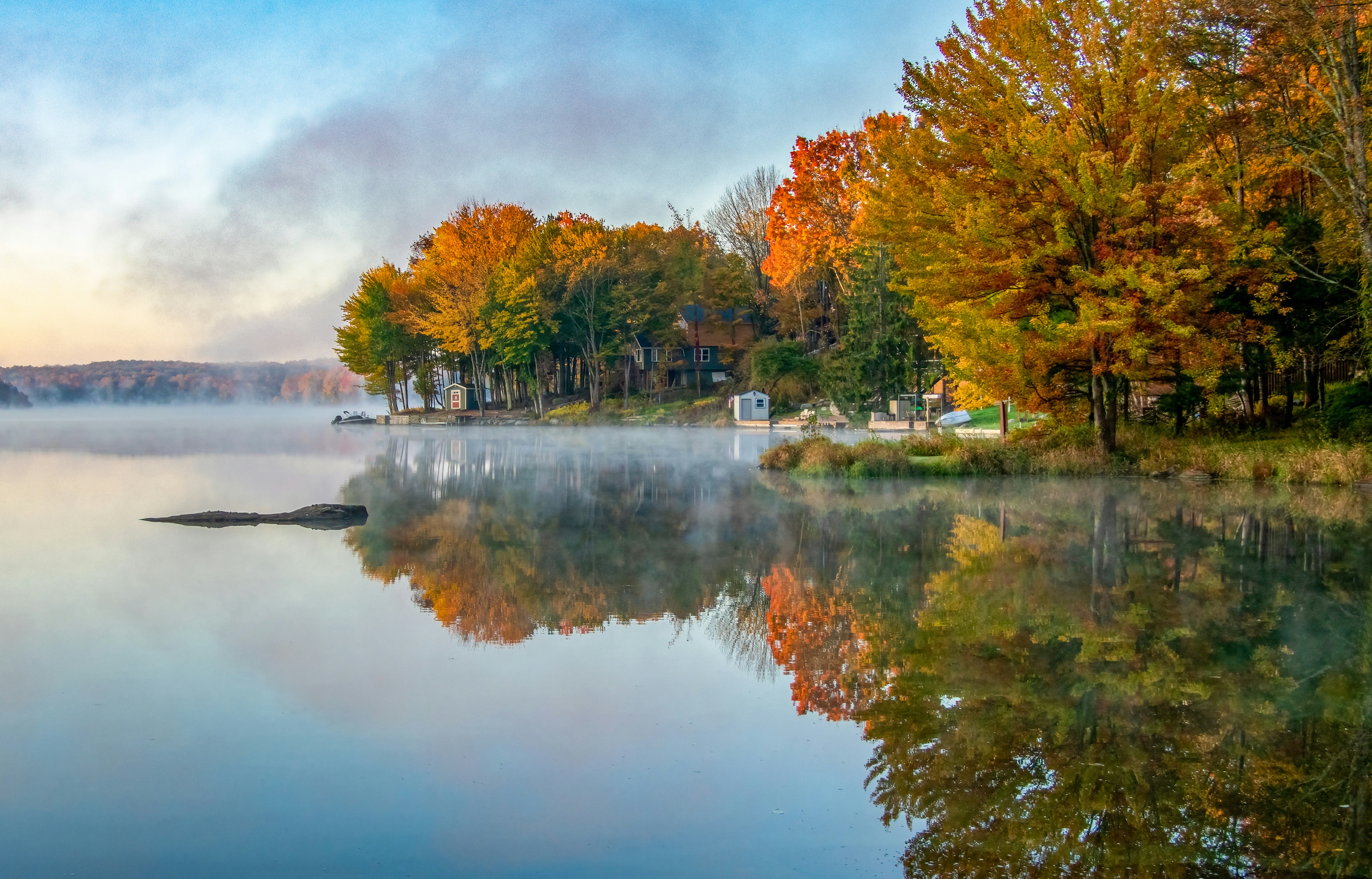 a body of water surrounded by trees in the fall