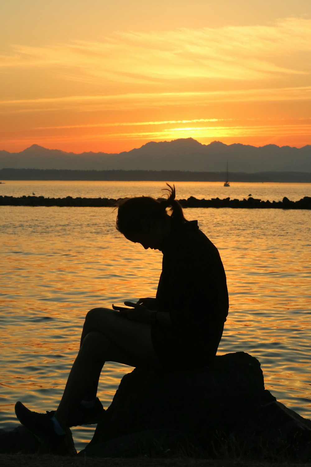 a person sitting on a rock in front of a body of water