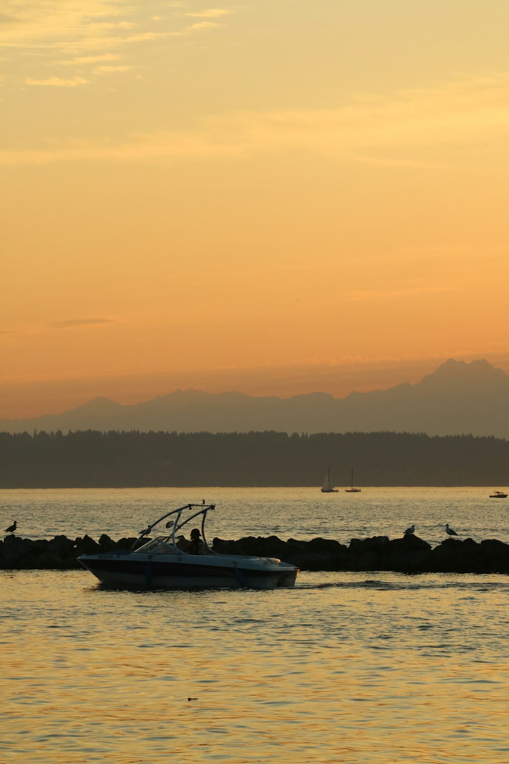 a boat in the water at sunset with mountains in the background