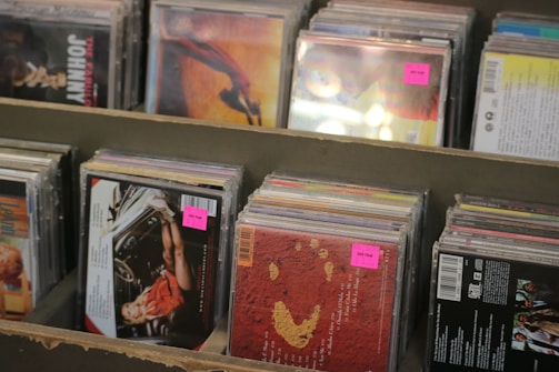 Several rows of music CDs arranged in a display shelf, with pink price stickers on some of them.