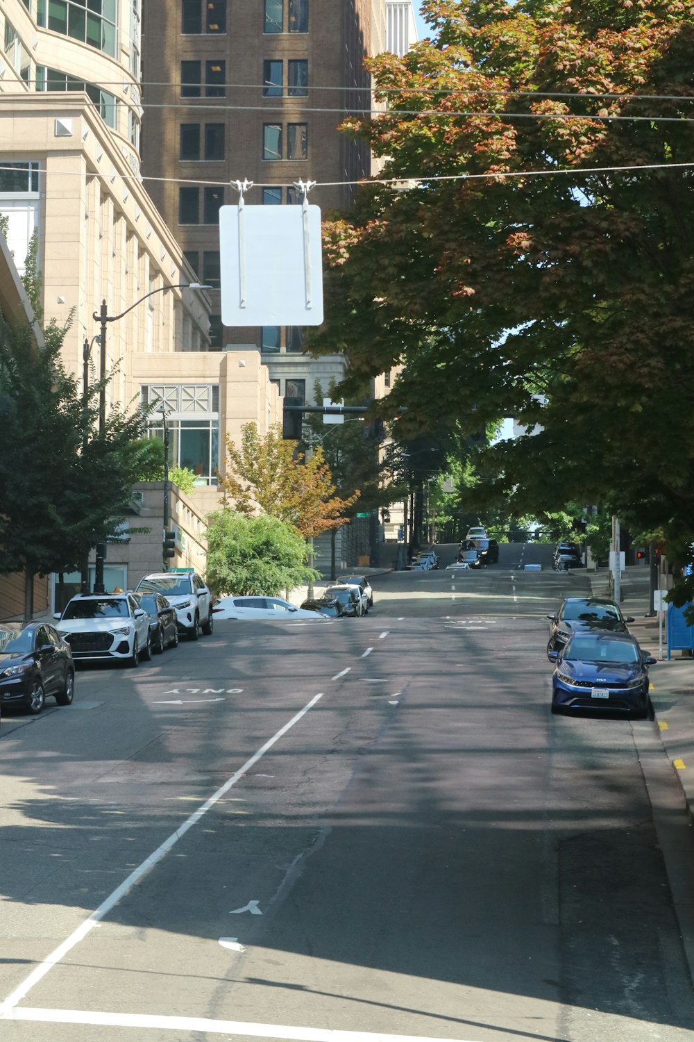 a city street lined with parked cars and tall buildings