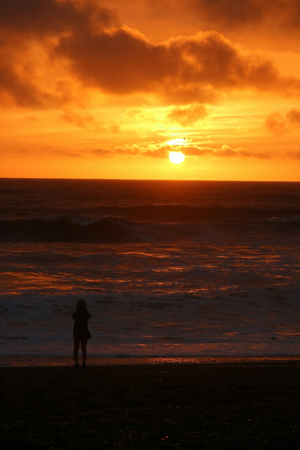 a person standing on a beach at sunset