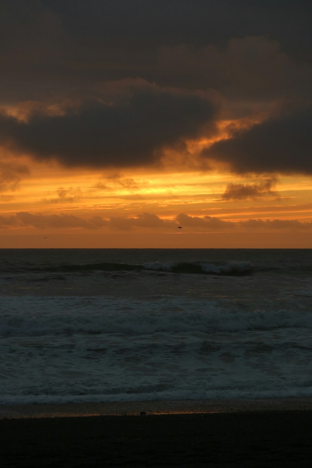 the sun is setting over the ocean with waves