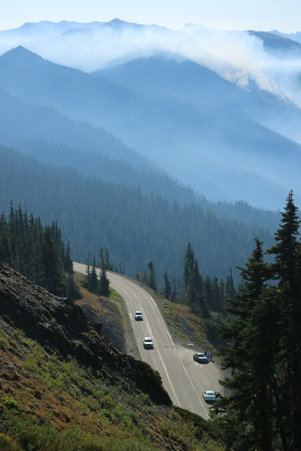 a view of a mountain road with cars driving on it