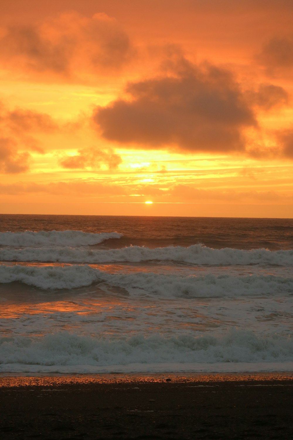 the sun is setting over the ocean with waves