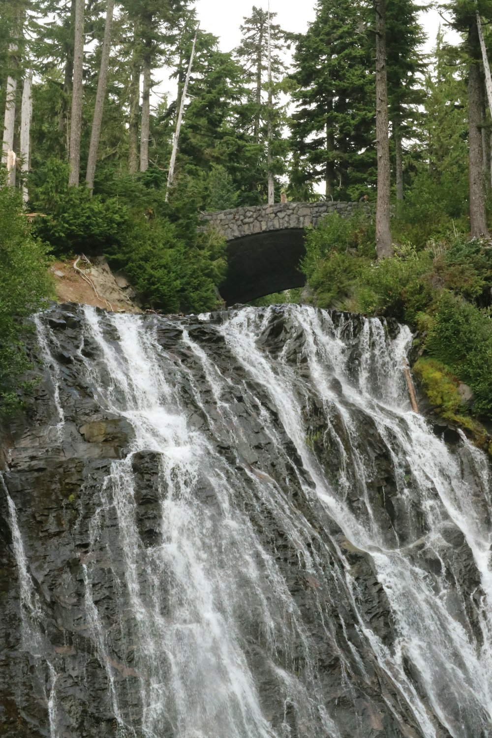 a waterfall with a bridge in the background