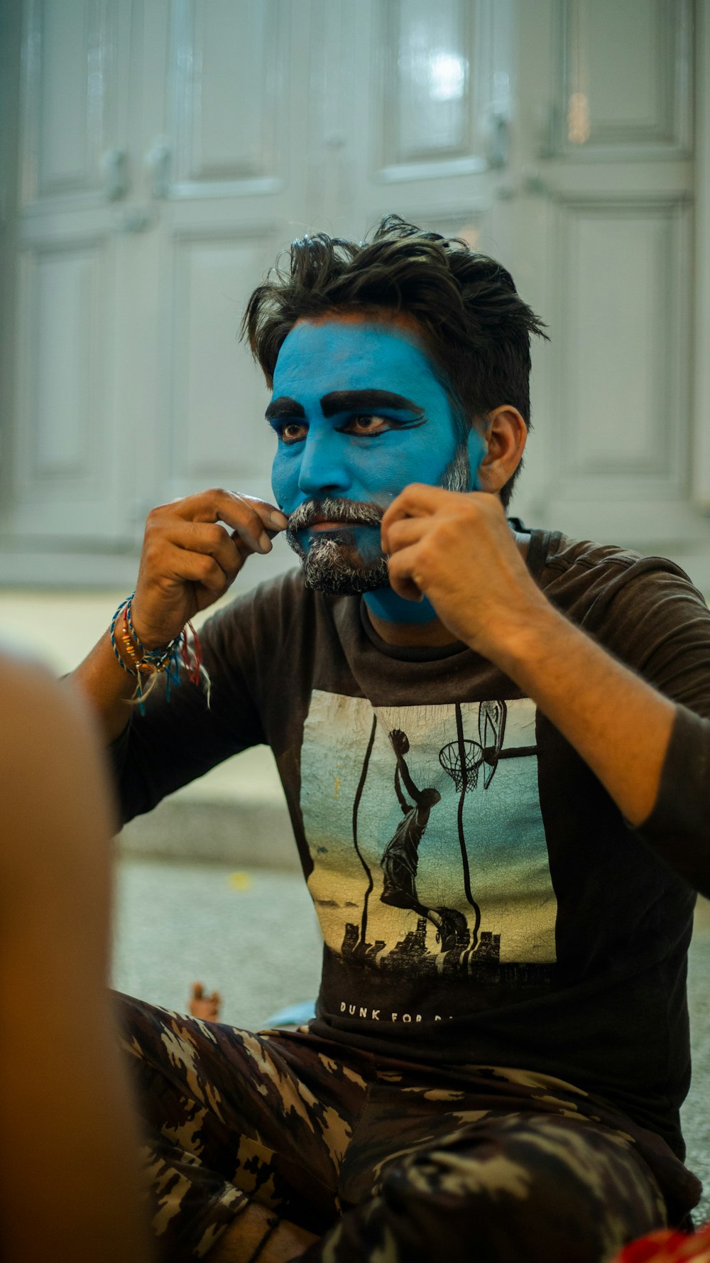 a man with a blue face sitting on the ground