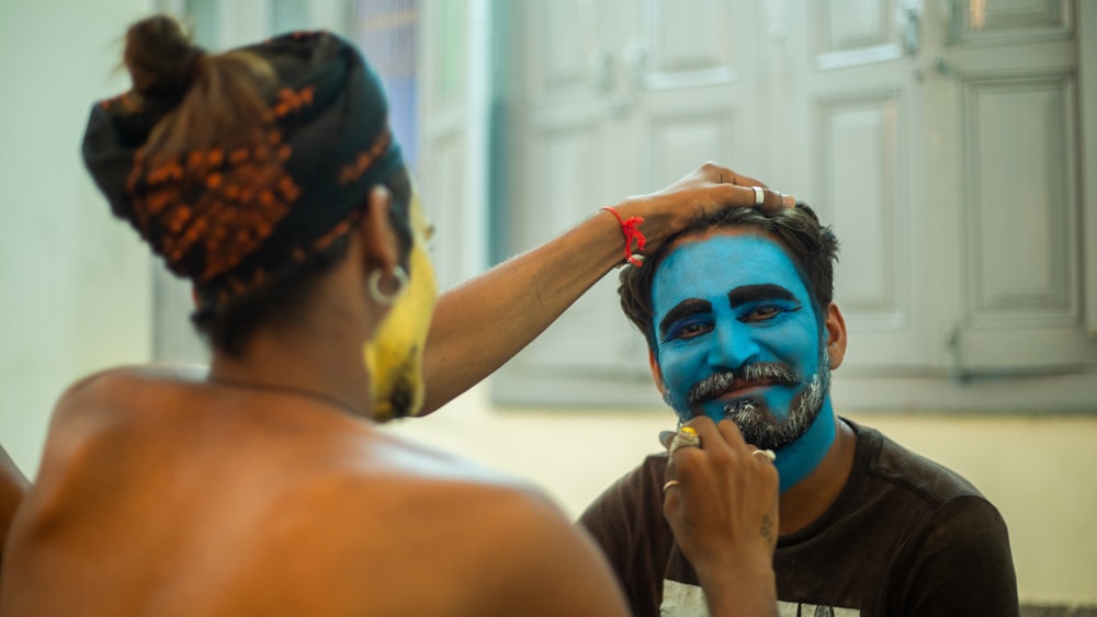 a man is getting his face painted blue