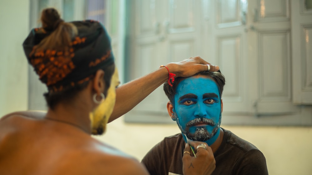 a man is getting his face painted blue