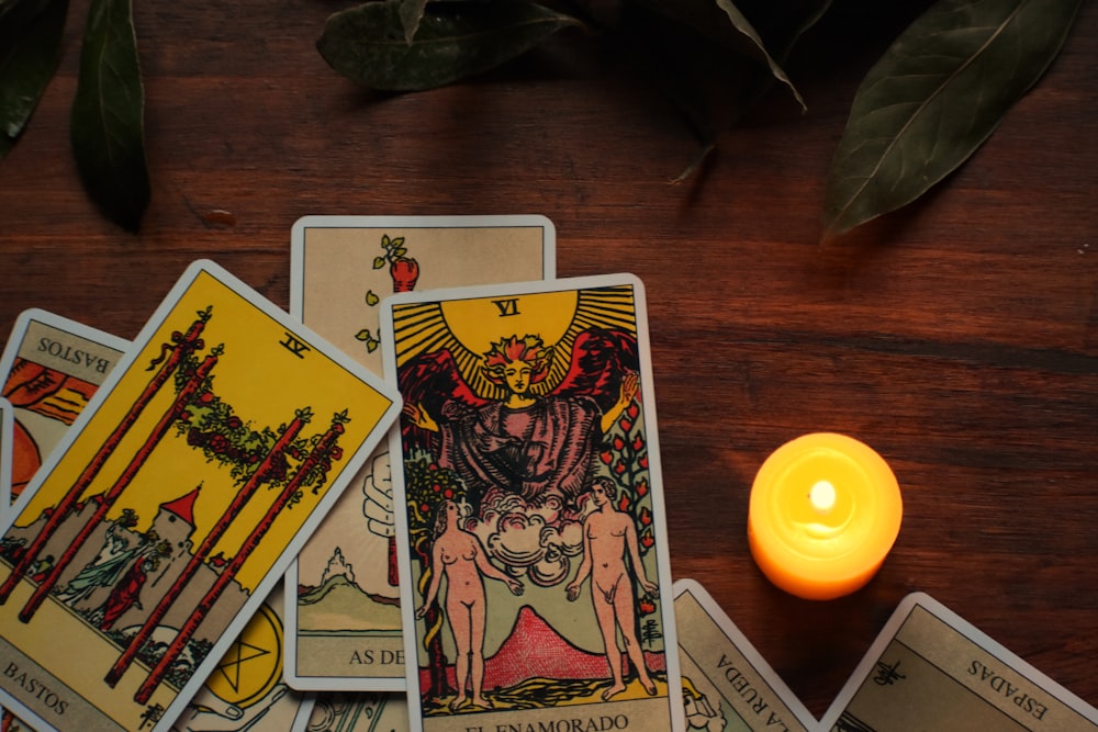 Una vela sentada junto a un juego de cartas del tarot