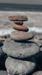 Close-up of a handmade Celtic tide creation featuring natural beach stones and driftwood against a soft Irish shoreline background.