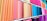 Various brightly colored fabric rolls are neatly arranged on shelves in a fabric store. The fabrics range from pastel pinks and peaches to vibrant blues, purples, and greens.