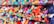 Rows of neatly arranged colorful fabric rolls fill the shelves with a wide range of patterns and textures. The fabrics are tightly packed, displaying a rich array of colors including reds, blues, greens, yellows, and purples. Each roll appears unique, contributing to a vibrant, visually appealing tapestry.