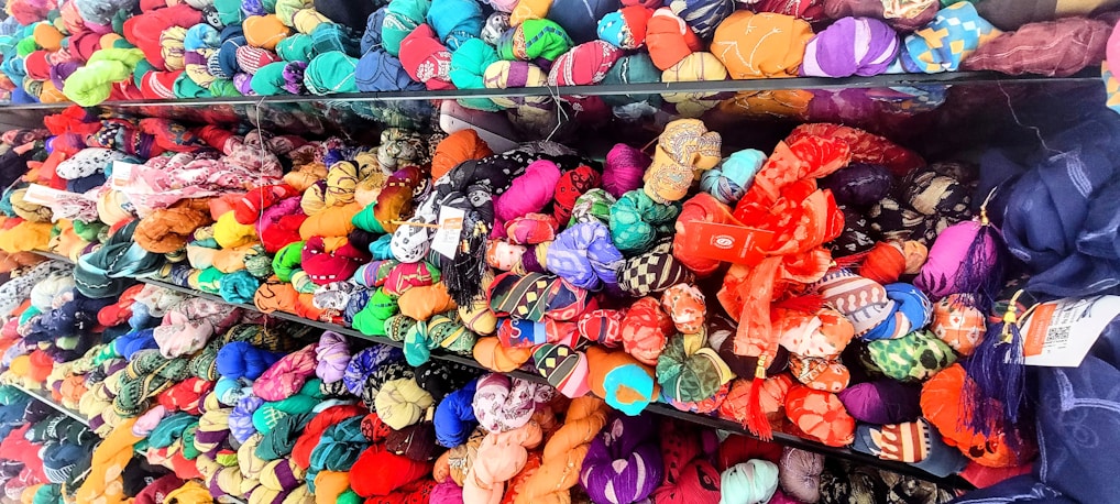 Close-up of vibrant, finely woven fabric rolls stacked neatly in a bright workshop.