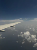 Close-up of a sleek airplane wing cutting through clear blue skies, symbolizing journeys and travel.