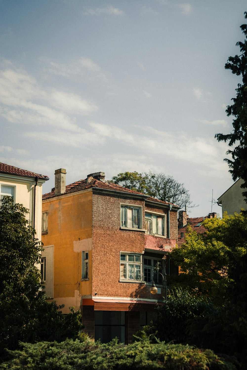 a tall brick building sitting next to a lush green forest