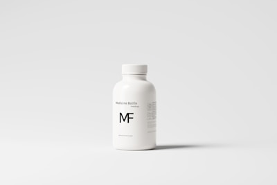 A white plastic bottle with a screw top, labeled 'Medicine Bottle mockup' and the letters 'MF' in bold. The bottle is placed against a plain, light gray background, with some small text details visible on the right side.
